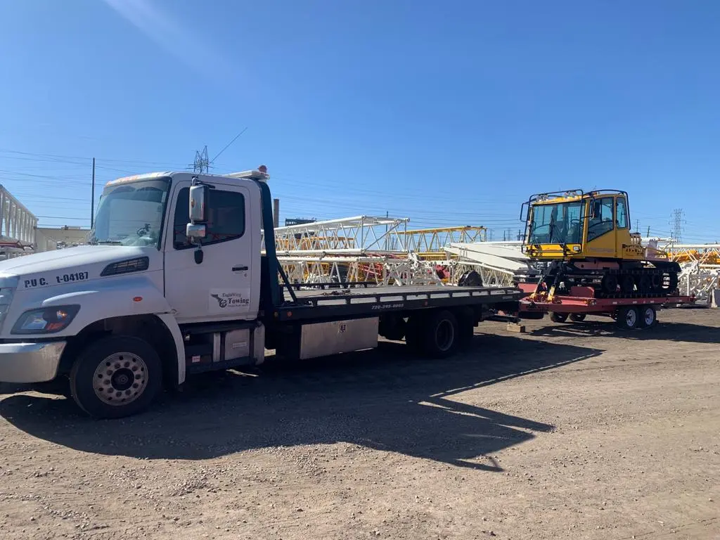 White heavy duty tow truck hauling construction equipment in Denver, CO